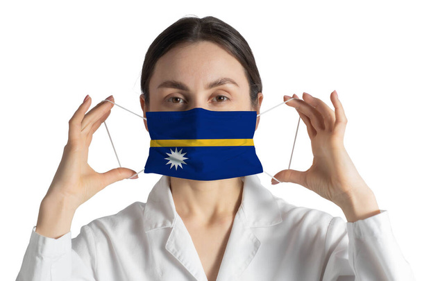 Respirator with flag of Nauru Doctor puts on medical face mask isolated on white background. - Photo, Image