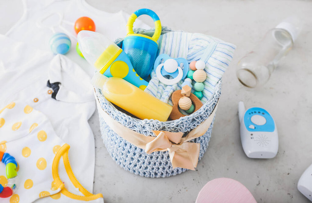 Cesta con regalos y ropa para bebé sobre fondo claro - Foto, imagen