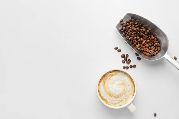 ホットカプチーノと白を背景にコーヒー豆とスクープのカップ - 写真・画像