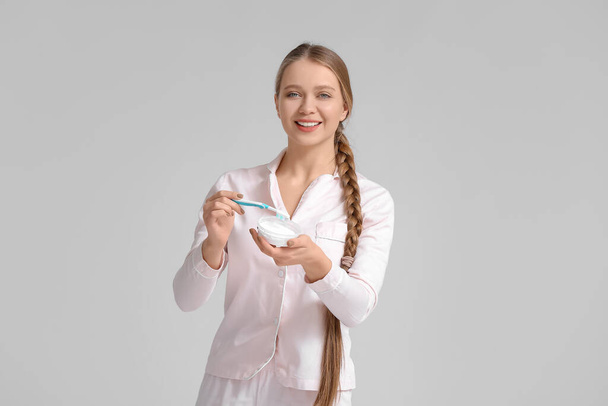 Молода жінка чистить зуби на сірому фоні
 - Фото, зображення