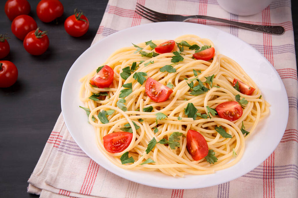 Pasta spaghetti with cherry tomatoes and parsley on a dark background, delicious, natural. - Foto, imagen