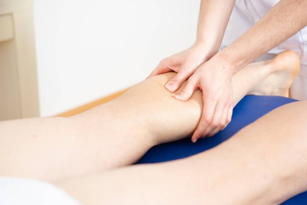The hands of a physiotherapist massaging the calf muscle. - Foto, Bild
