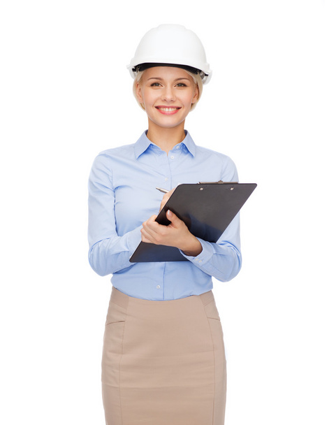 smiling businesswoman in helmet with clipboard - Foto, Imagem