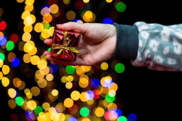 A person holding Christmas tree decorations with bokeh lights in the background - Photo, Image