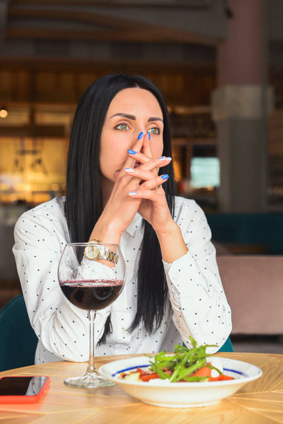 Young attractive woman having a healthy lunch in restaurant. Caucasian female with black hair dining. Eating out concept, eating alone in restaurant due to Covid-19 pandemic. - Foto, immagini