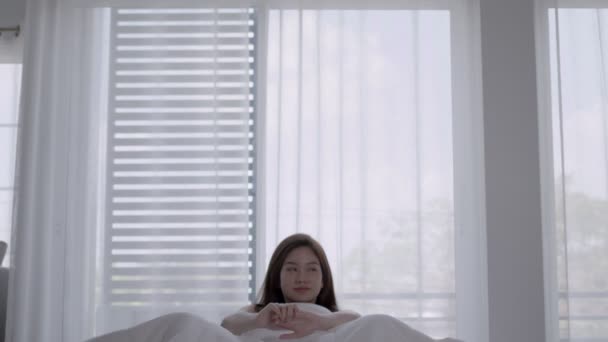 Aasian naiset herätä onnellinen ja hymyillä valkoinen sänky makuuhuoneessa. - Materiaali, video