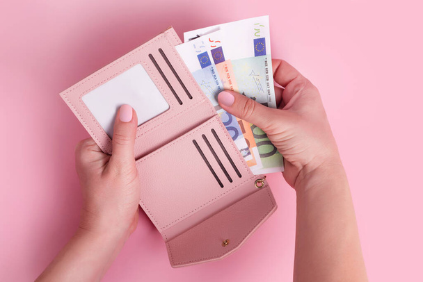 Hands holding wallet. Pink leather wallet with euro money in female hands. Closeup on a woman's hands taking European bank notes out of purse and counting. Concept of money, finances, shopping, cash - Photo, Image