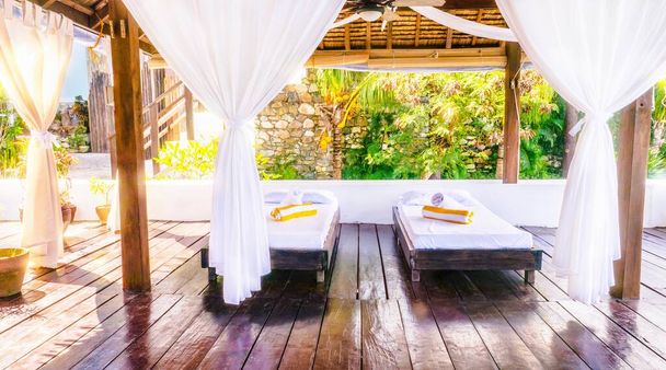 A light and airy, rustic, open-air massage room in the Philippines, with two simple beds on a wooden floor and pretty, boho style white curtains. - Photo, Image