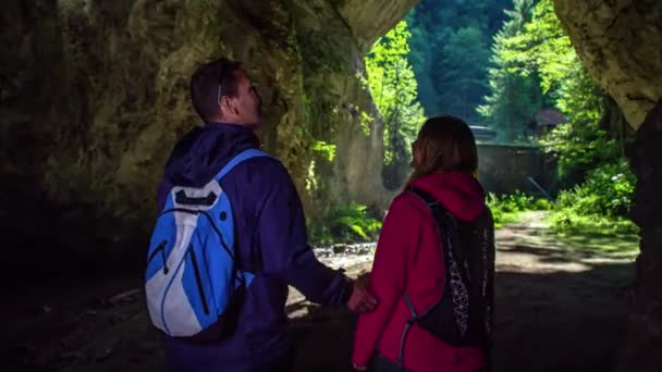 Paar wandert durch Höhle in Richtung Eingang und weist auf Felsmerkmale hin. - Filmmaterial, Video