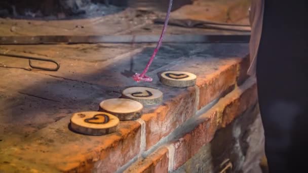 Primer plano de un artesano marcando corazones en pequeñas piezas de madera con un palo de hierro rojo caliente - Imágenes, Vídeo