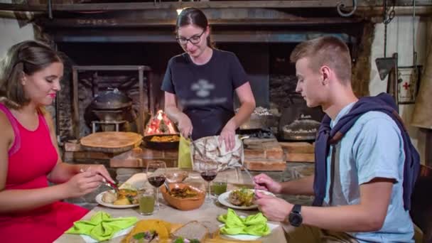 ウエートレスのスローモーションショットは、夕食を持っているカップルの前でパンの自家製ローフをスライス - 映像、動画