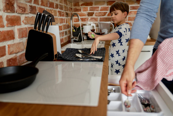 Ο γιος πλένει τα πιάτα μετά το πρωινό                                - Φωτογραφία, εικόνα
