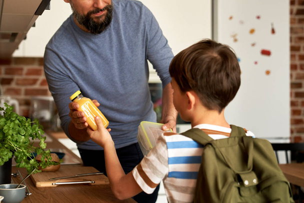 Primer plano de padre dando hijo almuerzo caja para la escuela - Foto, Imagen