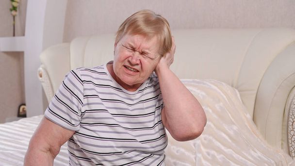 Starší žena na posteli s bolestí ucha. - Fotografie, Obrázek