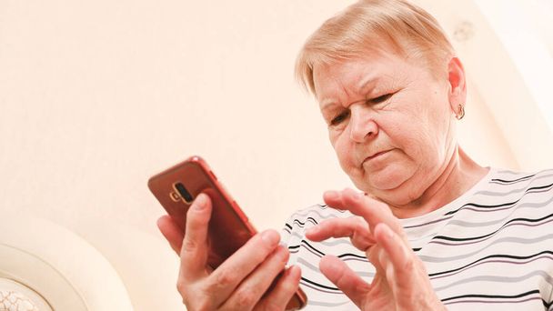 An elderly woman examining a mobile phone. - Zdjęcie, obraz
