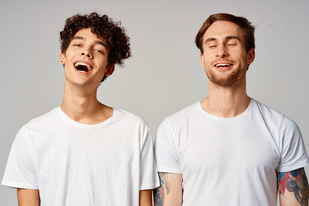 twee vrienden in witte t-shirts leuke emoties geïsoleerde achtergrond - Foto, afbeelding