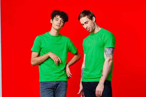 two friends in green t-shirts are standing next to tin with their hands emotions - Photo, Image