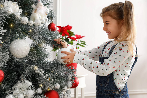 かわいいです女の子飾るクリスマスツリーに家 - 写真・画像