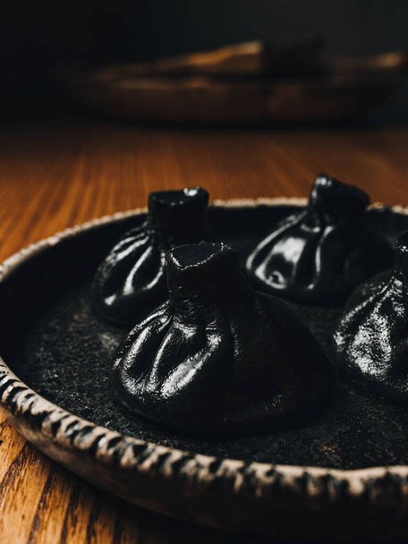Zwarte khinkali op zwarte plaat. Georgische levensmiddelen - Foto, afbeelding