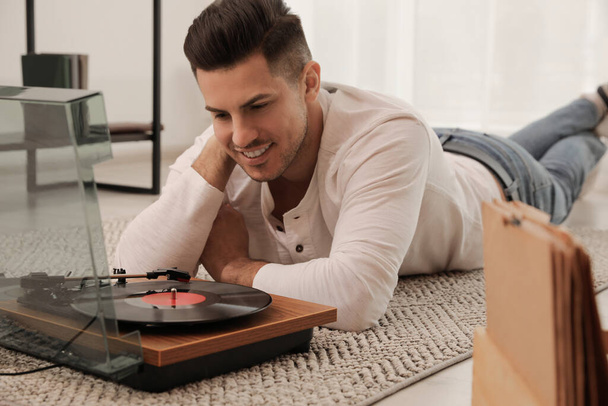 Happy man listening to music with turntable while lying on floor at home - Fotoğraf, Görsel