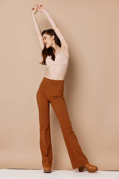  woman model in trousers and in a bra raised her hands up - Foto, imagen