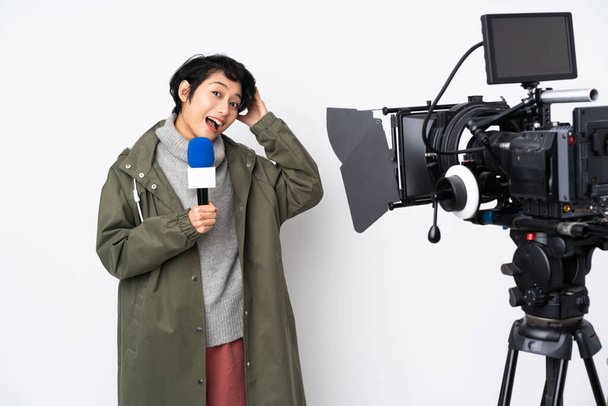 Reportera vietnamita sosteniendo un micrófono y reportando noticias sorprendida y señalando con el dedo hacia un lado - Foto, imagen