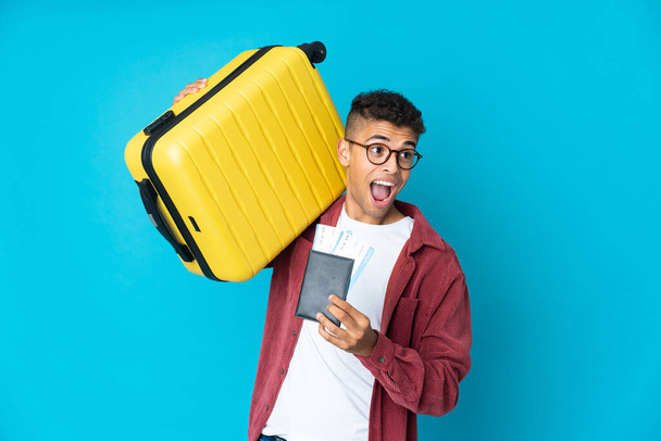 若いですブラジル人男性上隔離された背景で休暇でスーツケースとパスポート - 写真・画像