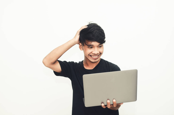 Un homme asiatique portant un T-shirt noir décontracté porte un ordinateur portable avec l'expression de trouver des idées - Photo, image