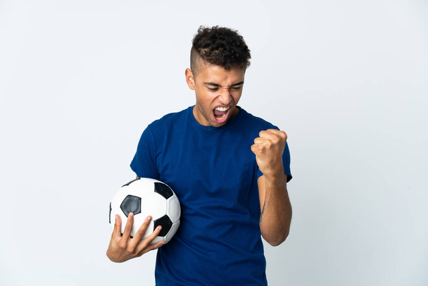 Fiatal brazil férfi elszigetelt háttérrel focilabdával ünnepli a győzelmet - Fotó, kép