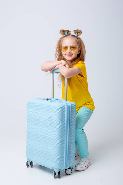 little girl traveler with a suitcase on a white background - Valokuva, kuva