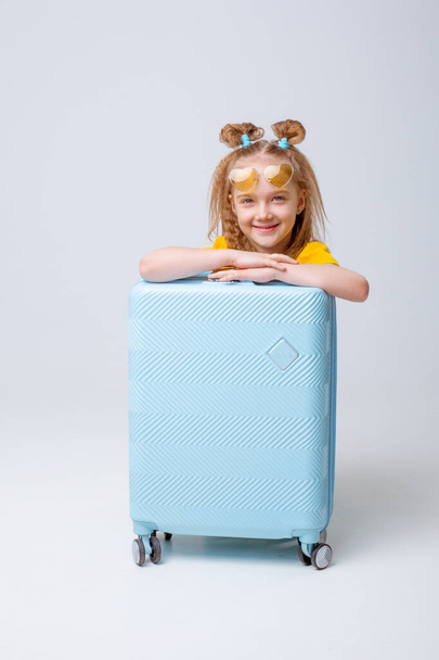 маленькая девочка путешественница с чемоданом на белом фоне - Фото, изображение