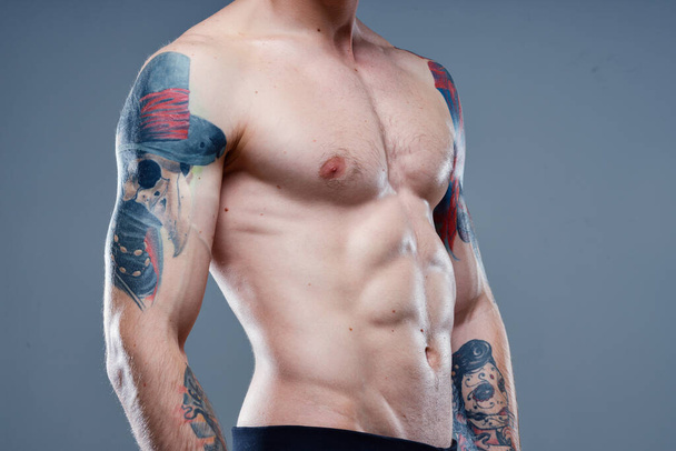 sexy athlete with naked torso and pumped up muscles tattoo gray background model - Foto, Imagem