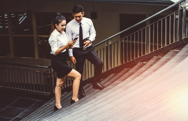 Üzletember és nő használja a mobiltelefon a munka. Találkozók a kereskedelmi tevékenységek előmozdítása. Együtt hozzon létre egy kölcsönösen előnyös lépcsőkön.  - Fotó, kép