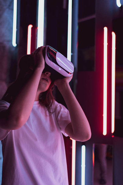 Vertical shot - a virtual reality helmet on a woman close-up. Neon light. Futuristic future - Фото, зображення