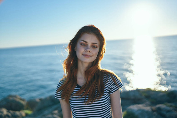 Deniz güneşinin yanındaki dağlarda tişörtlü güzel bir kadın. Yüksek kalite fotoğraf - Fotoğraf, Görsel
