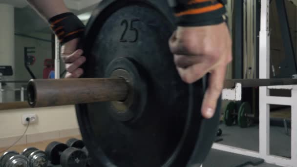 Athlete bodybuilder puts weight on barbell - Footage, Video