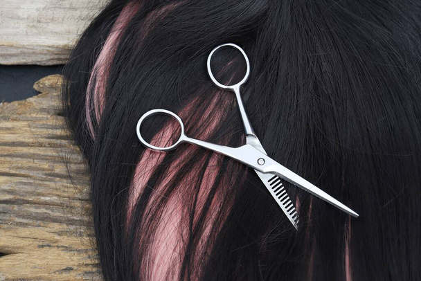 Hair cutting shears and black pink hair on brown wood table - Photo, image