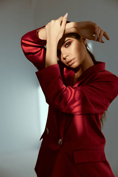 mulher bonita segurando mão perto de rosto moda posando casaco vermelho - Foto, Imagem