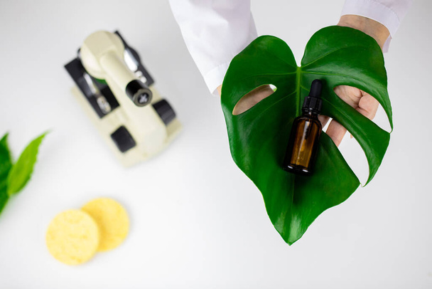 Face serum on green leaf on white lab background, plant-based cosmetics concept - Photo, Image