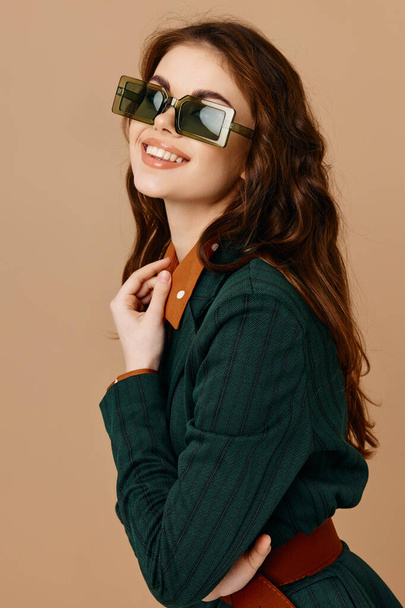 μοντέρνα γυναίκα με κοστούμι μοντέρνο στυλ γυαλιά ηλίου μπεζ φόντο - Φωτογραφία, εικόνα