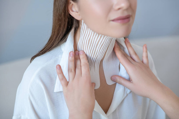 Close up of a young woman visiting beauty center and having taping procedure on her neck muscle - Zdjęcie, obraz