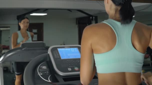 Atletische vrouw loopt op een loopband in een fitnessclub. - Video