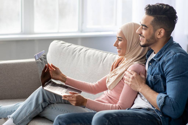 Side view of muslim couple using laptop at home - Photo, Image