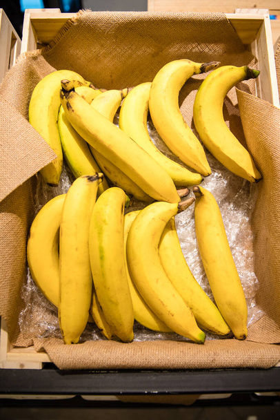 Sluitingen van bananen in doos op plank in supermarkt - Foto, afbeelding
