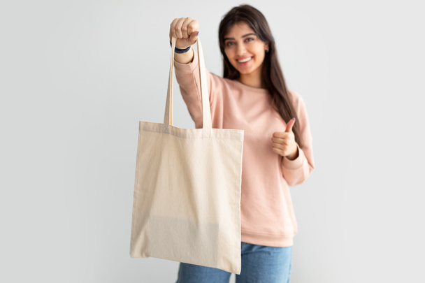 Mujer alegre de pie con bolsa de lona en blanco - Foto, Imagen