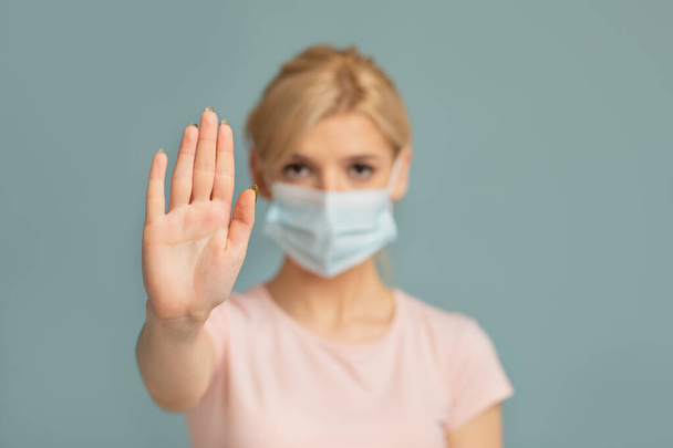 Fermare l'epidemia mondiale di COVID-19. Donna in maschera protettiva che mostra il gesto STOP con palmo aperto su sfondo grigio studio - Foto, immagini