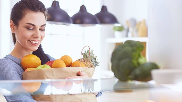 Smiling woman taking a fresh fruit out of the fridge, healthy food concept - Foto, imagen