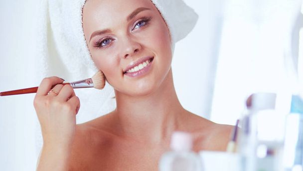 A picture of a young woman applying face powder in the bathroom - Foto, Bild