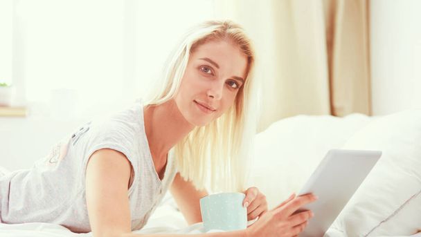 Girl holding digital tablet with blank screen and smiling at camera in bedroom - Foto, Bild