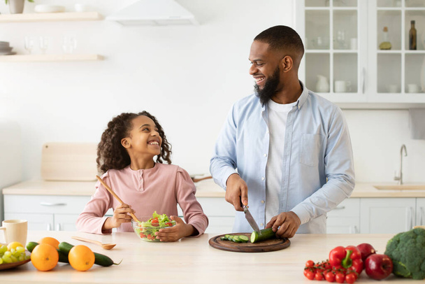 Afroamericano papà e figlia cucinare gustosa insalata fresca - Foto, immagini